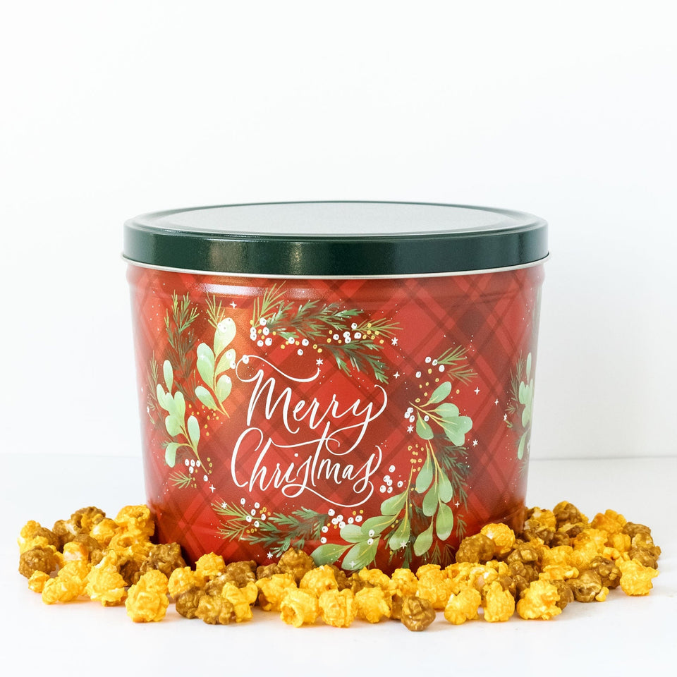 Merry Christmas themed popcorn bucket with cheddar and caramel popcorn on a white background